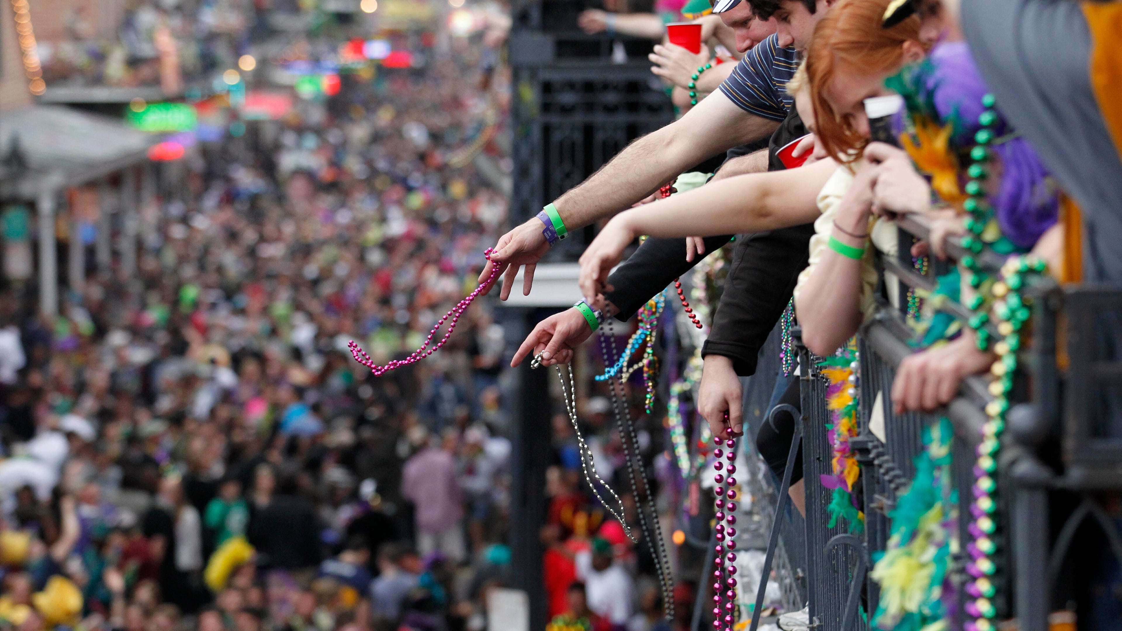 FILE - Revelers throw beads from the balcony of the Royal Sonesta Hotel onto crowds on Bourbon Street during Mardi Gras festivities in the French Quarter in New Orleans, March 8, 2011. (AP Photo/Gerald Herbert, File)