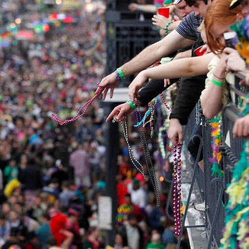 FILE - Revelers throw beads from the balcony of the Royal Sonesta Hotel onto crowds on Bourbon Street during Mardi Gras festivities in the French Quarter in New Orleans, March 8, 2011. (AP Photo/Gerald Herbert, File)