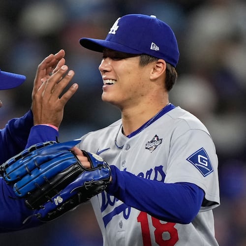 Los Angeles Dodgers pitcher Yoshinobu Yamamoto celebrates with right fielder Teoscar Hernández after throwing compete game against the Toronto Blue Jays in Game 2 of baseball's World Series, Saturday, Oct. 25, 2025, in Toronto. (AP Photo/Brynn Anderson)
