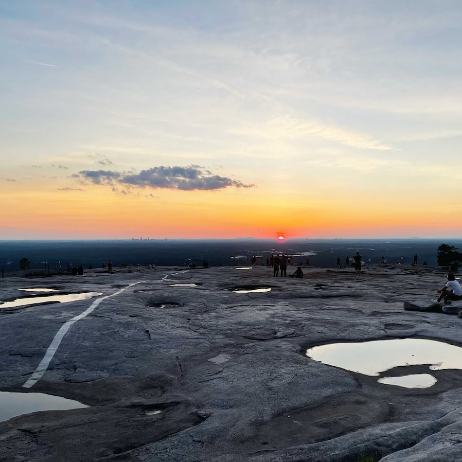 Near the end of the longest day of the year, Georgians rest atop Stone Mountain to watch the sunset behind the Atlanta skyline. (Richard Watkins/AJC)