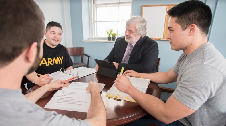 Chase Keith (back to camera), a student in the Veterans Legal Clinic, and Andy Bastone (second from left) and Nick Mugge (right) discuss the clinic with director Alex Scherr, offering their perspectives as the first three veterans to receive scholarships to UGA’s School of Law. CONTRIBUTED BY UNIVERSITY OF GEORGIA SCHOOL OF LAW