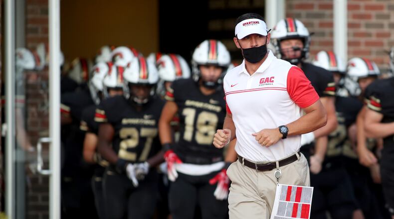 GAC coach Tim Hardy runs out of the field house with football players before Friday's game against Lovett in Norcross. (Jason Getz/Special to the AJC)