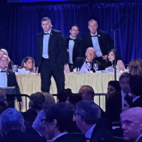U.S. Secret Service agents surround President Donald Trump before he was taken from the stage after a shooting incident outside the ballroom during the White House Correspondents Dinner, Saturday, April 25, 2026, in Washington. (AP Photo/Alex Brandon)