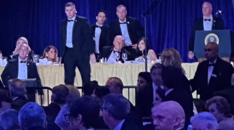 U.S. Secret Service agents surround President Donald Trump before he was taken from the stage after a shooting incident outside the ballroom during the White House Correspondents Dinner, Saturday, April 25, 2026, in Washington. (AP Photo/Alex Brandon)