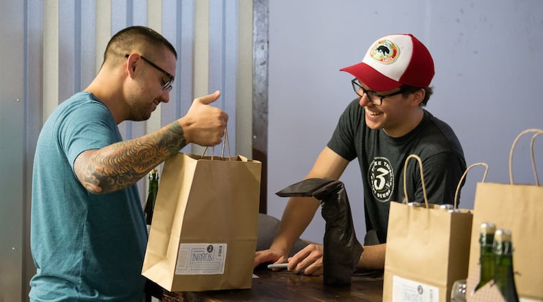 Joran Van Ginderachter, brewmaster at Three Taverns, gives a visitor his souvenir bottles of Inceptus at the brewery’s first bottle release on Sunday, Aug. 23. Van Ginderachte created the beer through the process of open spontaneous fermentation and captured a strain of Georgia wild yeast. Contributed by Kathy Reynolds / Three Taverns Brewery