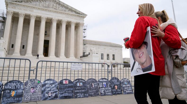 FILE - Jen Trejo holds a photo of her son Christopher as she is comforted outside the Supreme Court Dec. 4, 2023, in Washington. (AP Photo/Stephanie Scarbrough, File)