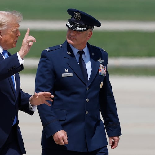 President Donald Trump, left, is escorted by Air Force Col. Christopher M. Robinson, commander of the 89th Airlift Wing, right, as he walk from Marine One to Air Force One, at Joint Base Andrews, Md., Tuesday, Aug. 4, 2026. (AP Photo/Luis M. Alvarez)