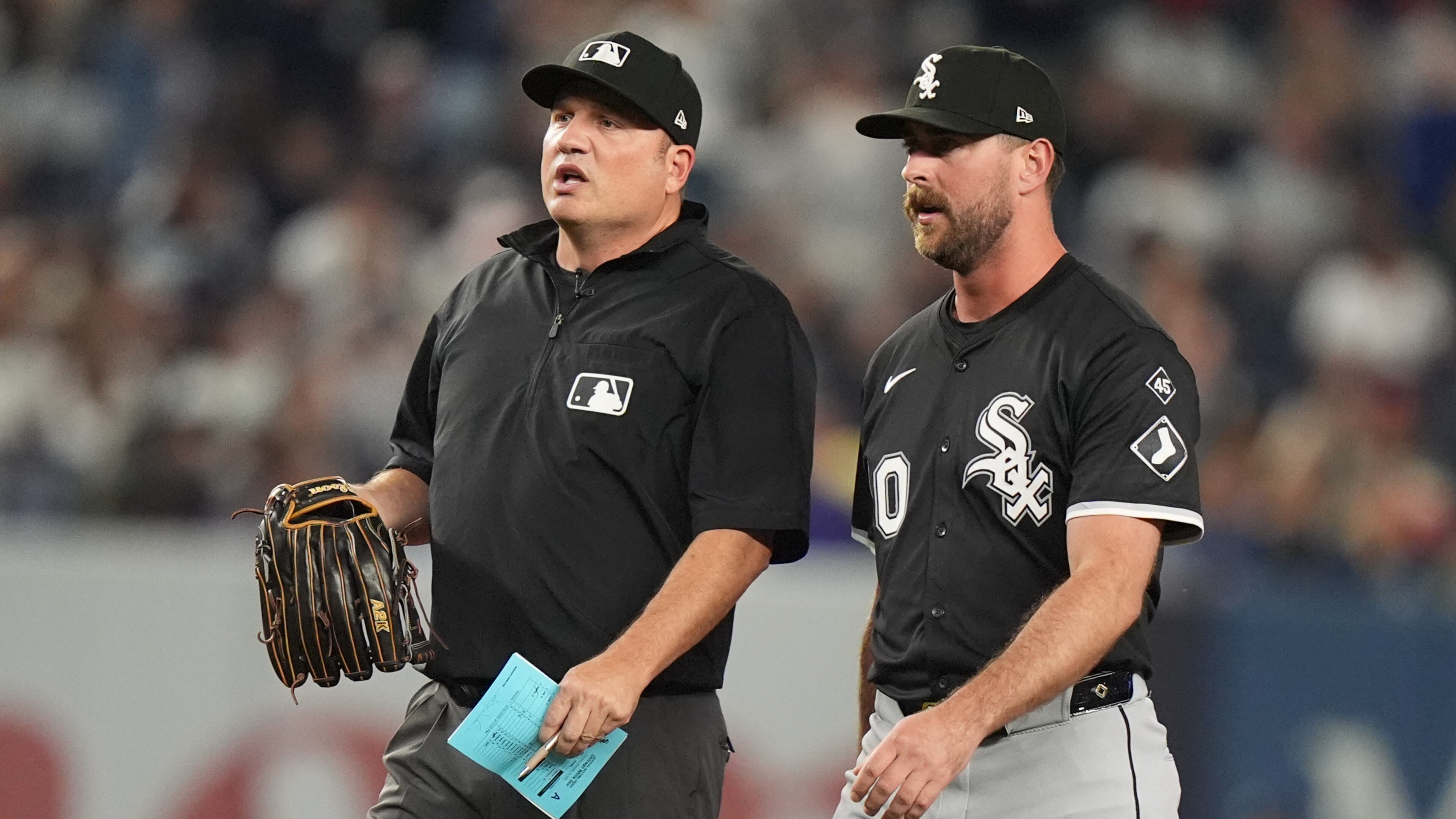 Umpire Dan Bellino holds the glove of Chicago White Sox pitcher Tyler Gilbert before he pitches during the fifth inning of a baseball game against the New York Yankees Thursday, Sept. 25, 2025, in New York. (AP Photo/Frank Franklin II)