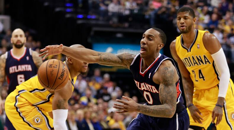 Atlanta Hawks guard Jeff Teague (0) reaches for the basketball after driving between Indiana Pacers forward Paul George, right, and Pacers forward David West in the first half of an NBA basketball game in Indianapolis, Sunday, April 6, 2014. (AP Photo/R Brent Smith)