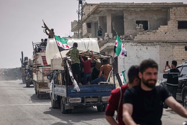 A man fires into the air from one of the trucks carrying some of the 60 displaced families who, supported by an NGO, are returning to their village after more than five years in the Atmeh camps near the Syrian-Turkish border, in Kafr Sijna, south of Idlib, Syria, Sunday, May 18, 2025. (AP Photo/Ghaith Alsayed)