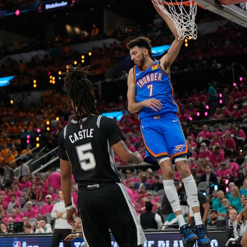 Oklahoma City Thunder center Chet Holmgren (7) hangs on the rim next to San Antonio Spurs guard Stephon Castle (5) after a dunk during the second half of Game 3 in the Western Conference finals NBA basketball playoffs series Friday, May 22, 2026, in San Antonio. (AP Photo/Ashley Landis)