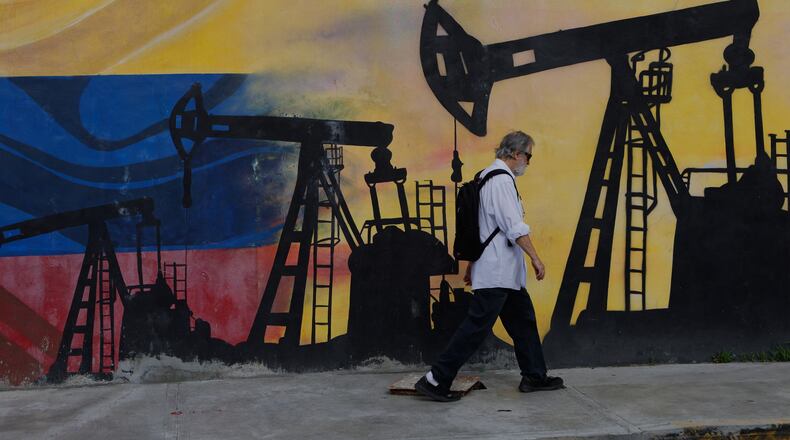 A pedestrian walks past a mural featuring oil wells in Caracas, Venezuela, Saturday, Aug 29, 2026, a day after President Donald Trump announced a deal giving the United States a stake in Venezuela’s oil reserves. (AP Photo/Pedro Mattey)