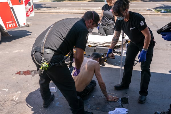 FILE - Salem Fire Department Capt. Matt Brozovich, left, and Falck Northwest ambulance personnel help treat a man experiencing heat exposure during a heat wave in Salem, Ore., June 26, 2021. (AP Photo/Nathan Howard, File)