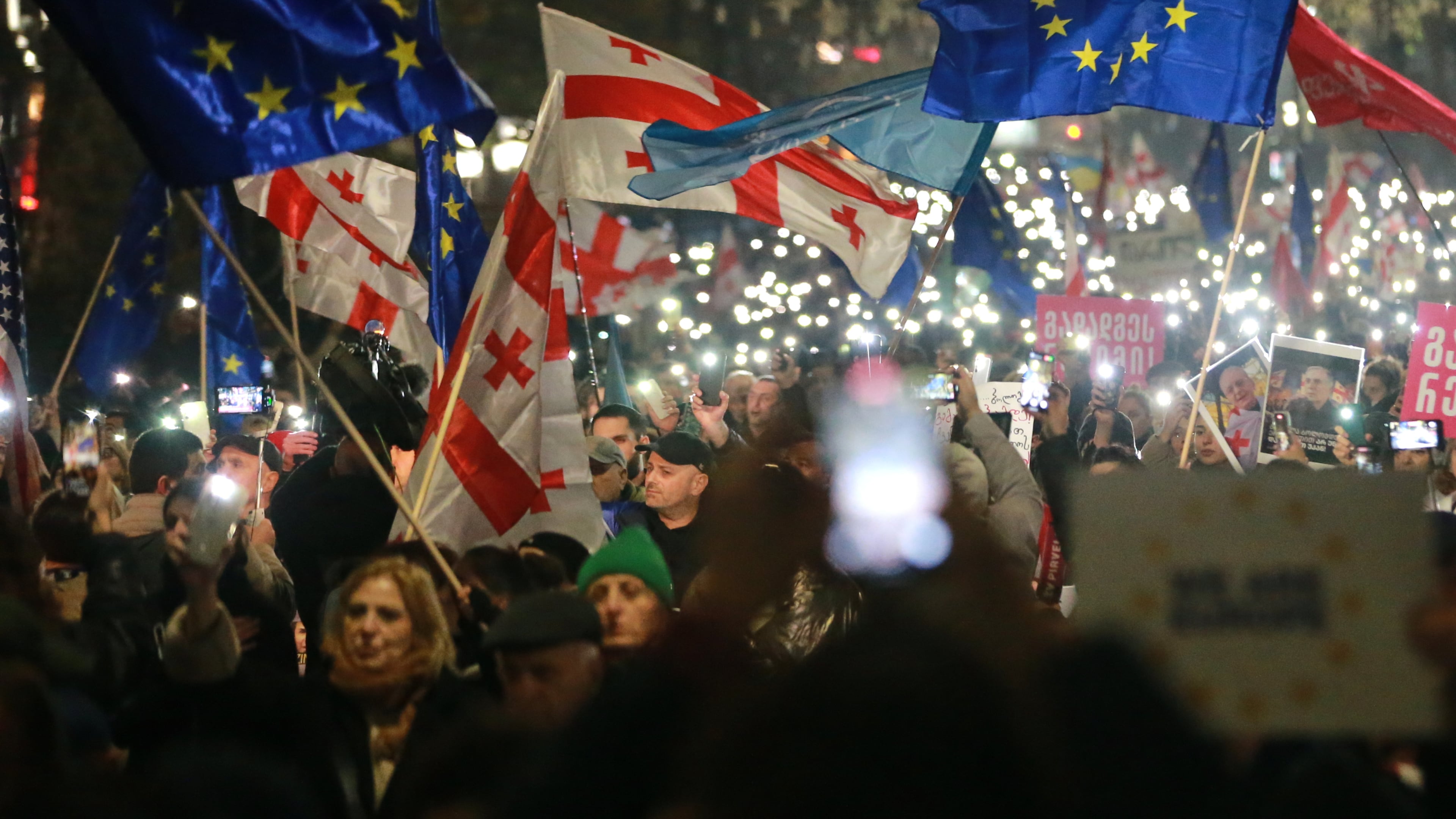 Demonstrators with Georgian and EU flags gather in the Georgian capital of Tbilisi, on Friday, Nov. 28, 2025, to mark 365 days of non-stop protests against the government's decision to halt talks on joining the European Union. (AP Photo/Zurab Tsertsvadze)