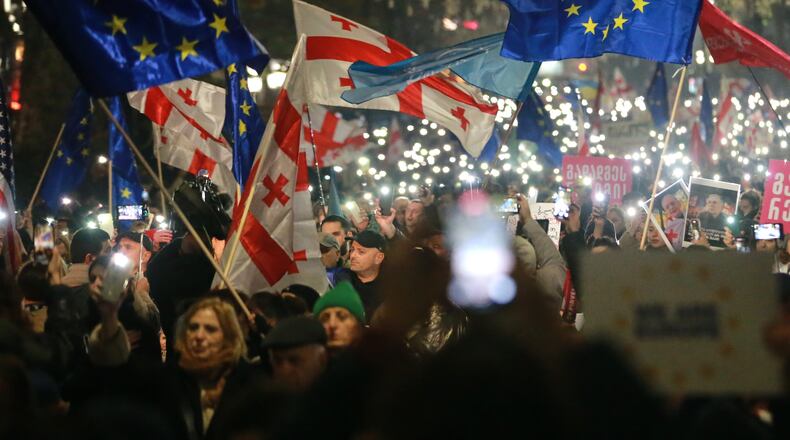Demonstrators with Georgian and EU flags gather in the Georgian capital of Tbilisi, on Friday, Nov. 28, 2025, to mark 365 days of non-stop protests against the government's decision to halt talks on joining the European Union. (AP Photo/Zurab Tsertsvadze)
