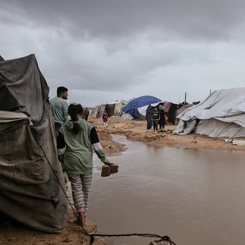 Palestinians walk through a flooded area in a temporary tent camp after heavy rainfall in Gaza City, Thursday, March 26, 2026 (AP Photo/Jehad Alshrafi)