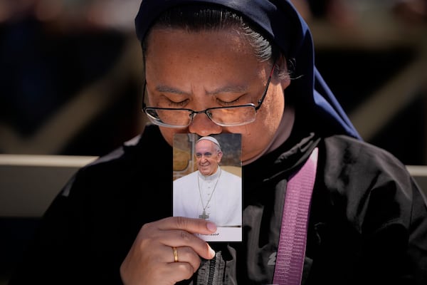 A nun holds a phot of Pope Francis while attending his funeral in St. Peter's Square at the Vatican, Saturday, April 26, 2025. (AP Photo/Andreea Alexandru)