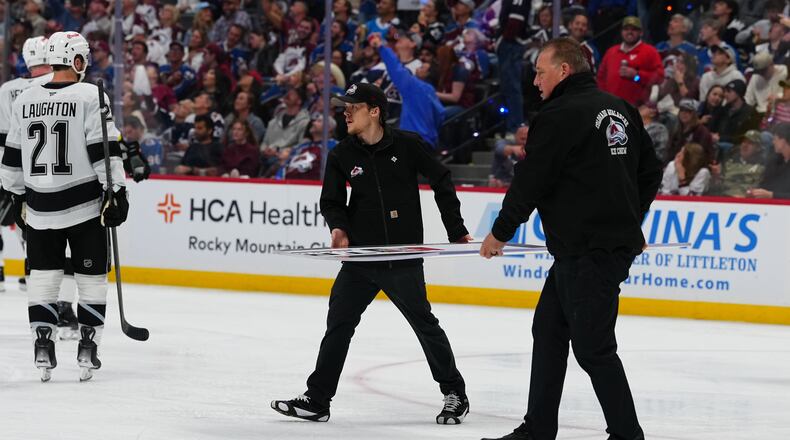 Members of the Colorado Avalanche conversion crew carry a new piece of glass to the Los Angeles Kings' bench during the second period of Game 2 in the first round of the NHL hockey Stanley Cup playoffs against the Colorado Avalanche, Tuesday, April 21, 2026, in Denver. (AP Photo/Jack Dempsey)