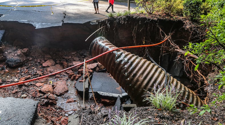 September 8, 2021 Cobb County: Onlookers overlook the road that was washed away at Fawn Place at East Lake Parkway in Marietta on Wednesday, Sept. 8, 2021 after torrential downpours of rain overnight brought flooding and damage to the Cobb County area. Residents and emergency officials in Cobb County worked throughout the day, Wednesday to clean up after intense storms and heavy downpours resulted in flash floods overnight. On Tuesday evening, the clouds opened up and dropped more than three inches of rain on much of the metro Atlanta area, Channel 2 Action News reported. In Cobb, the storms brought floods that damaged cars and homes. Marietta was hit with 4.37 inches of rain, which caused storm drains to overflow. “That’s just too much water, too fast,” Channel 2 meteorologist Brian Monahan said. On social media, Cobb residents posted videos and photos of the severe flooding conditions they saw. Some neighbors described their typically quiet, manicured streets as river rapids. In other areas, the water rose so high that cars were partially submerged. Crews worked overnight and into Wednesday morning to pull cars off the streets after the flooding left them damaged. (John Spink / John.Spink@ajc.com)