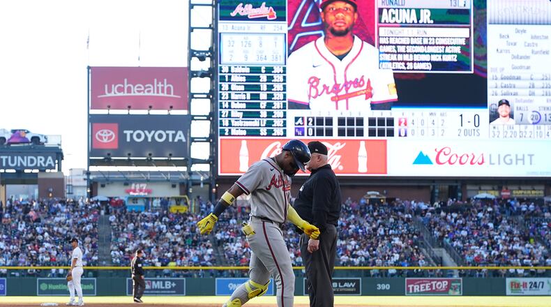Atlanta Braves' Ronald Acuña Jr., center left, walks gingerly after being injured while running out a groundout as first base umpire Bill Miller, center right, looks on in the second inning of a baseball game against the Colorado Rockies, Saturday, May 2, 2026, in Denver. (AP Photo/David Zalubowski)