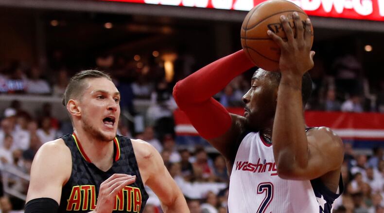 Washington Wizards guard John Wall, right, looks for a receiver while Atlanta Hawks forward Mike Muscala, left, defends during the first half in Game 1 of a first-round NBA basketball playoff series, in Washington, Sunday, April 16, 2017. (AP Photo/Manuel Balce Ceneta)