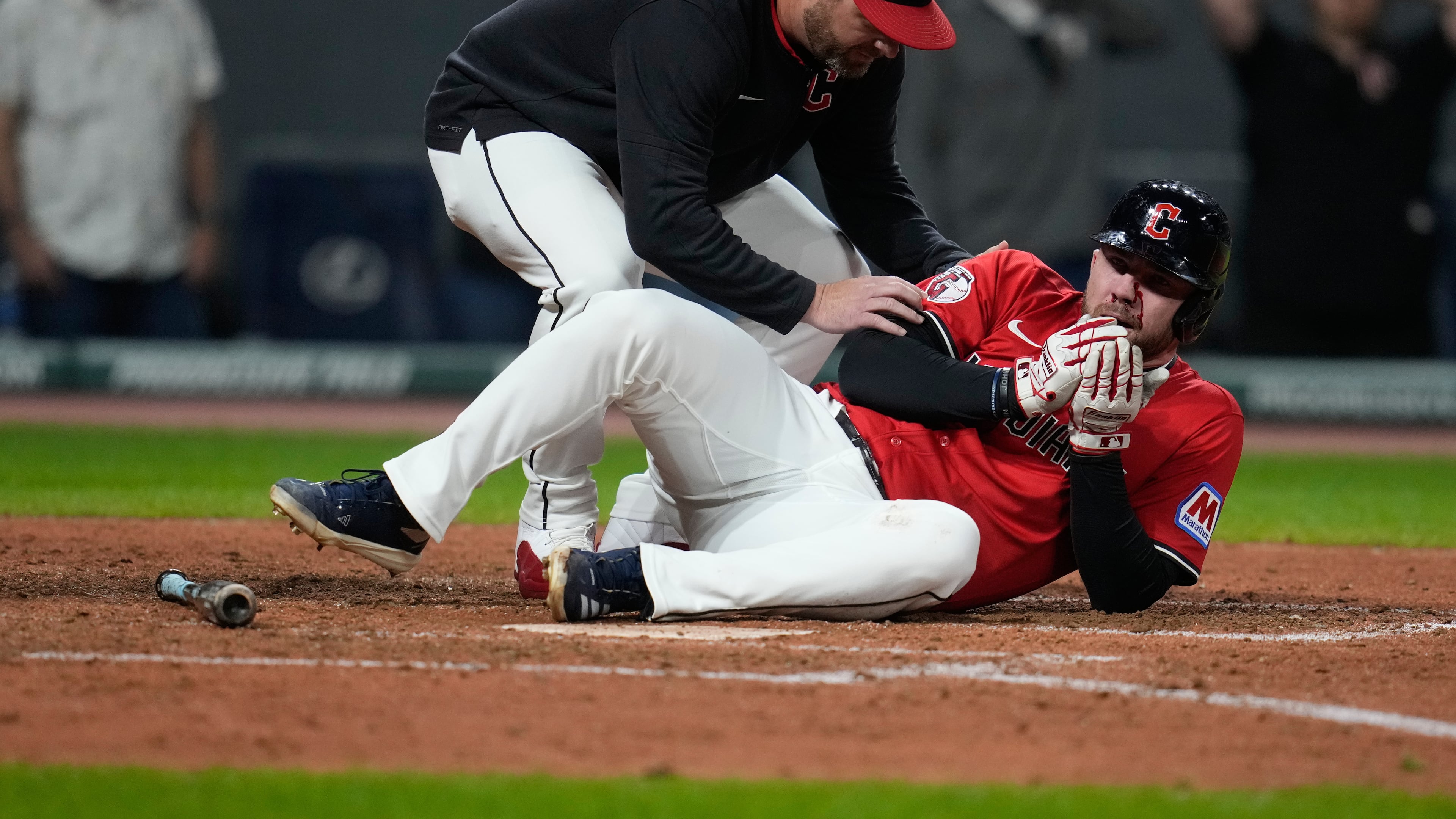 Cleveland Guardians manager Stephen Vogt, left, attends to David Fry after Fry was hit in the face with his own bunt in the sixth inning of a baseball game against the Detroit Tigers in Cleveland, Tuesday, Sept. 23, 2025. (AP Photo/Sue Ogrocki)