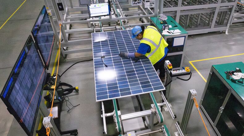 A worker makes a visual inspection of one of the solar panels as it moves through the automated assembly line at the Qcells module production facility in Cartersville on Tuesday, April 2, 2024. (Steve Schaefer/steve.schaefer@ajc.com)