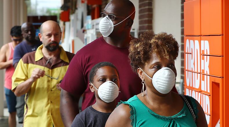 Customers wait in line to enter the Home Depot store at Midtown Place in March. Among retailers, Costco and Whole Foods have taken the lead in requiring customers to wear masks to shop, while others leave it up to the customer to decide. Curtis Compton ccompton@ajc.com