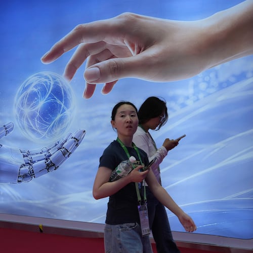 Visitors walk past a display depicting artificial intelligence and a human hand at the China International Supply Chain Expo in Beijing on Monday, June 22, 2026. (AP Photo/Ng Han Guan)