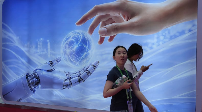 Visitors walk past a display depicting artificial intelligence and a human hand at the China International Supply Chain Expo in Beijing on Monday, June 22, 2026. (AP Photo/Ng Han Guan)