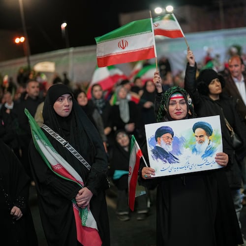 A woman holds a poster depicting the late Iran’s Supreme Leader Ayatollah Ali Khamenei, left, and the late revolutionary founder Ayatollah Ruhollah Khomeini during a pro-government gathering in a square in Tehran, Iran, Sunday, April 5, 2026. (AP Photo/Francisco Seco)