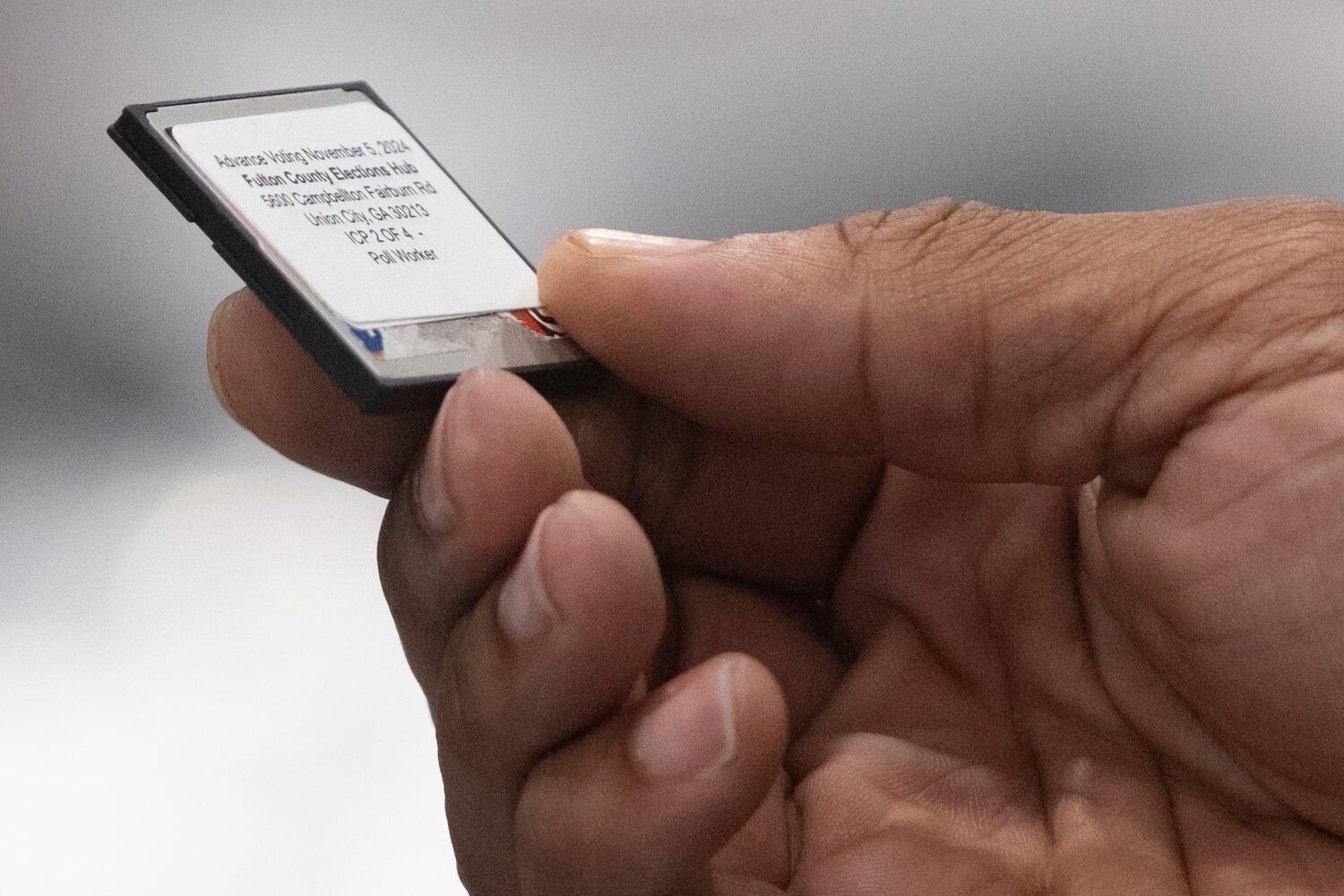A worker holds a memory card while loading advance voting results at the Fulton County election hub in Fairburn on Tuesday, Nov. 5, 2024.   Ben Gray for the Atlanta Journal-Constitution