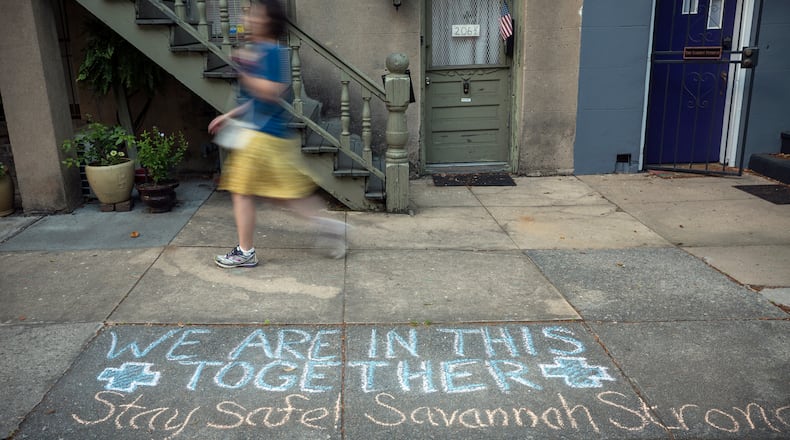 A Savannah resident in April walks past a sidewalk caulk message with an encouraging tone amid the pandemic. (Stephen B. Morton for The Atlanta Journal-Constitution)