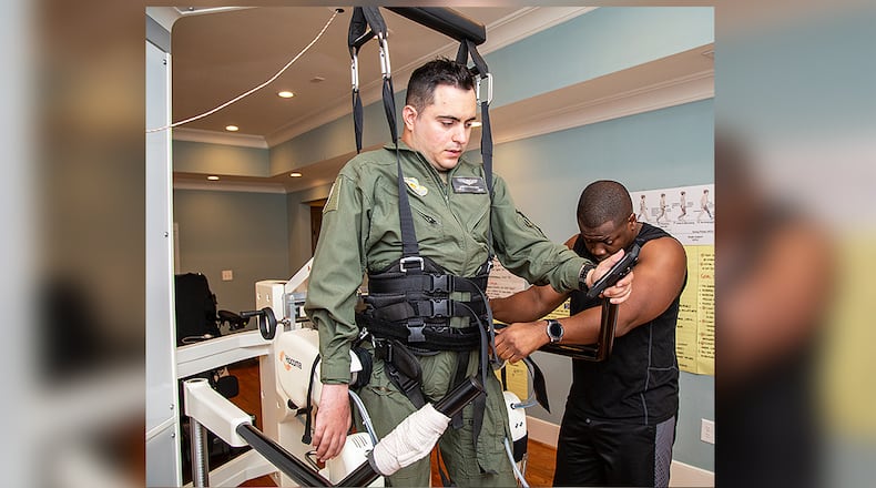 Ignacio Montoyo (left) gets help from Andre Ajayi preparing him to work out on a "Lokomat," a robot assisted locomotor training orthosis, in Atlanta on Monday August 12th, 2019. He was paralyzed in an accident while a student at Georgia Tech but persevered to get his degree and now works to improve the mobility of the paralyzed. (Photo by Phil Skinner)
