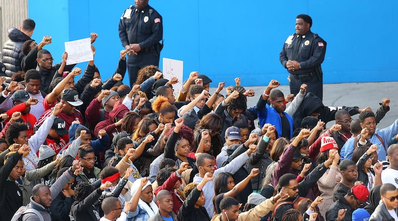Police officers look on while Morehouse College students join others in a rally and protest at the CNN Center last year after the shooting death of Ferguson, Mo., teen Michael Brown. CURTIS COMPTON / CCOMPTON@AJC.COM