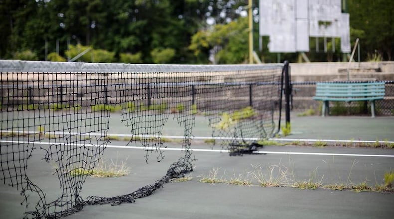 David GoldmanIn this July 19, 2016, photo, the derelict netting and scoreboard in the background on a tennis court stand at the Stone Mountain Tennis Center, home of the 1996 Summer Olympic Games tennis events, in Stone Mountain, Ga. The permanent tennis facility built in a corner of Stone Mountain Park quickly became a money loser and now sits idle, weeds growing through the outer courts and the scoreboard in disrepair. (AP Photo/David Goldman)