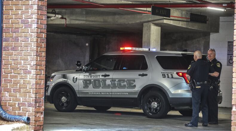 Dunwoody police officers stand outside the crime scene at the entrance of a parking deck where a man was found shot and killed underneath a Dunwoody apartment complex on April 8, 2019. JOHN SPINK/JSPINK@AJC.COM