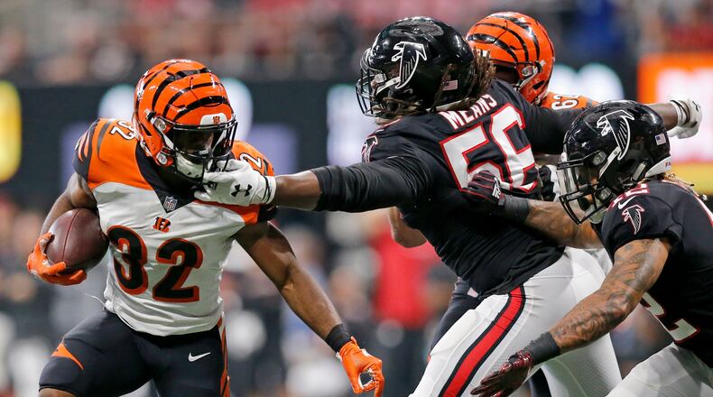Cincinnati Bengals running back Mark Walton (32) is grabbed by Atlanta Falcons defensive end Steven Means (56) on a carry in the fourth quarter of the NFL Week 5 game between the Atlanta Falcons and the Cincinnati Bengals at Mercedes-Benz Stadium in Atlanta on Sunday, Sept. 30, 2018. The Bengals scored a touchdown in the final seconds of the fourth quarter to win 37-36.