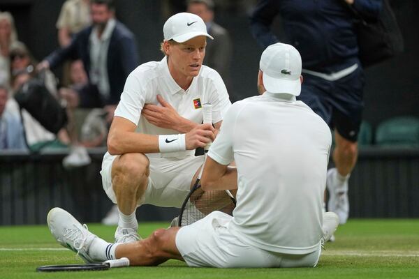 Italy's Jannik Sinner checks on Bulgaria's Grigor Dimitrov after he went down with an injury during a fourth round men's singles match at the Wimbledon Tennis Championships in London, Monday, July 7, 2025. (AP Photo/Kin Cheung)