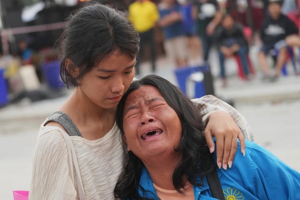 A woman reacts after being informed that her husband had died at the site of a collapsed under construction high-rise building in Bangkok, Thailand, Sunday, March 30, 2025. (AP Photo/Sakchai Lalit)