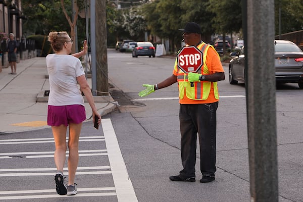 Larry McCrary helps pedestrians cross the road in front of Talley Street Upper Elementary. A native of Columbus, Mississippi, McCrary worked as a substitute teacher before moving to Atlanta in 1989. (Natrice Miller/AJC)