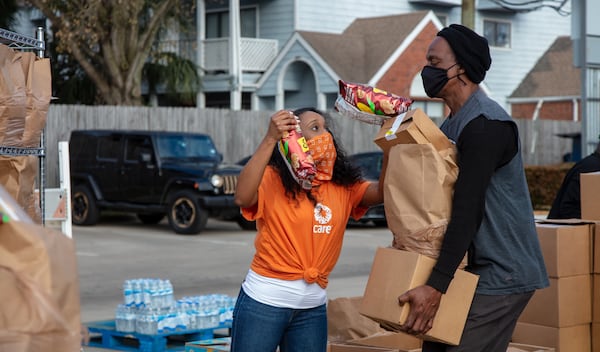 Gabby Dirden, a CARE contractor, helps Walter Ballard collect food and water for his family during Bethel's Heavenly Hands food and water distribution in Houston, Texas, on February 25, 2021. Hundreds of people received much needed food and water. The need was even greater following snowstorms that disrupted power and water service to much of Houston. Bethel's Heavenly Hands is a CARE partner. (Photo by Laura Noel/CARE)