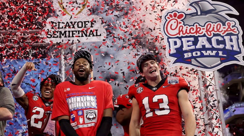 Georgia defensive back Christopher Smith and quarterback Stetson Bennett (13) celebrate their 42-41 win against Ohio State in the Peach Bowl College Football Playoff semifinal, at Mercedes-Benz Stadium,  Dec. 31, 2022, in Atlanta. (Jason Getz / Jason.Getz@ajc.com)
