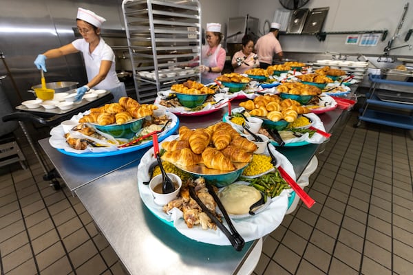 Large platters are shown with food ready to serve to each table of seniors during the Thanksgiving Celebration. (Jason Getz / AJC)