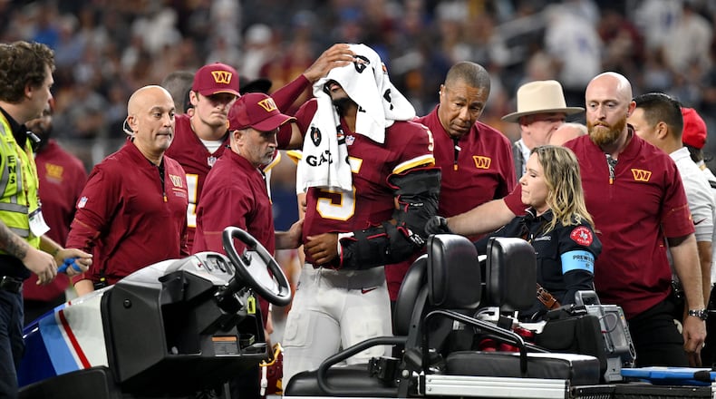 Trainers attend to Washington Commanders quarterback Jayden Daniels (5) after an apparent injury in the first half against the Dallas Cowboys during an NFL football game in Arlington, Texas, Sunday, Sept. 20, 2026. (AP Photo/Jessica Tobias)
