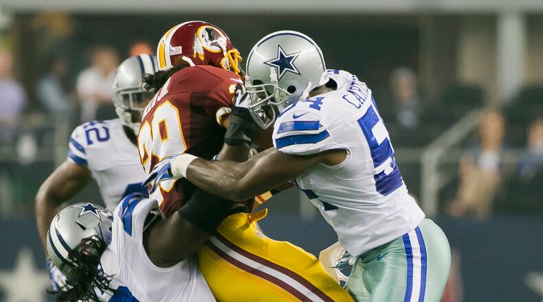 Dallas Cowboys (54) Bruce Carter and (70) Drake Nevis takes down Washington Redskins (29) Roy Helu Jr. during the first half of an NFL football game, in Arlington, Texas on Sunday, Oct. 13, 2013.