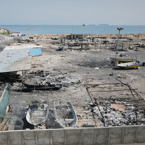 Backdropped by ships in the Strait of Hormuz, damage, according to local witnesses caused by several recent airstrikes during the U.S.-Israel military campaign, is seen on a fishing pier in the port of Qeshm island, Iran, Monday, April 13, 2026. (AP Photo/Asghar Besharati)
