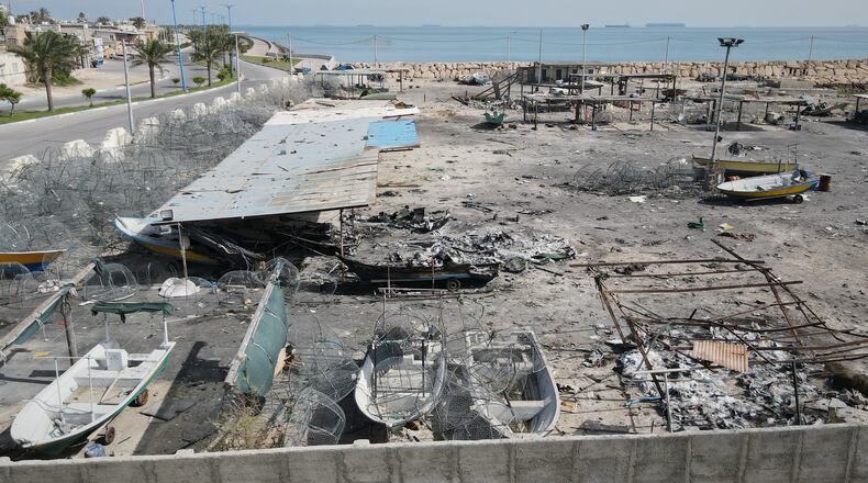 Backdropped by ships in the Strait of Hormuz, damage, according to local witnesses caused by several recent airstrikes during the U.S.-Israel military campaign, is seen on a fishing pier in the port of Qeshm island, Iran, Monday, April 13, 2026. (AP Photo/Asghar Besharati)