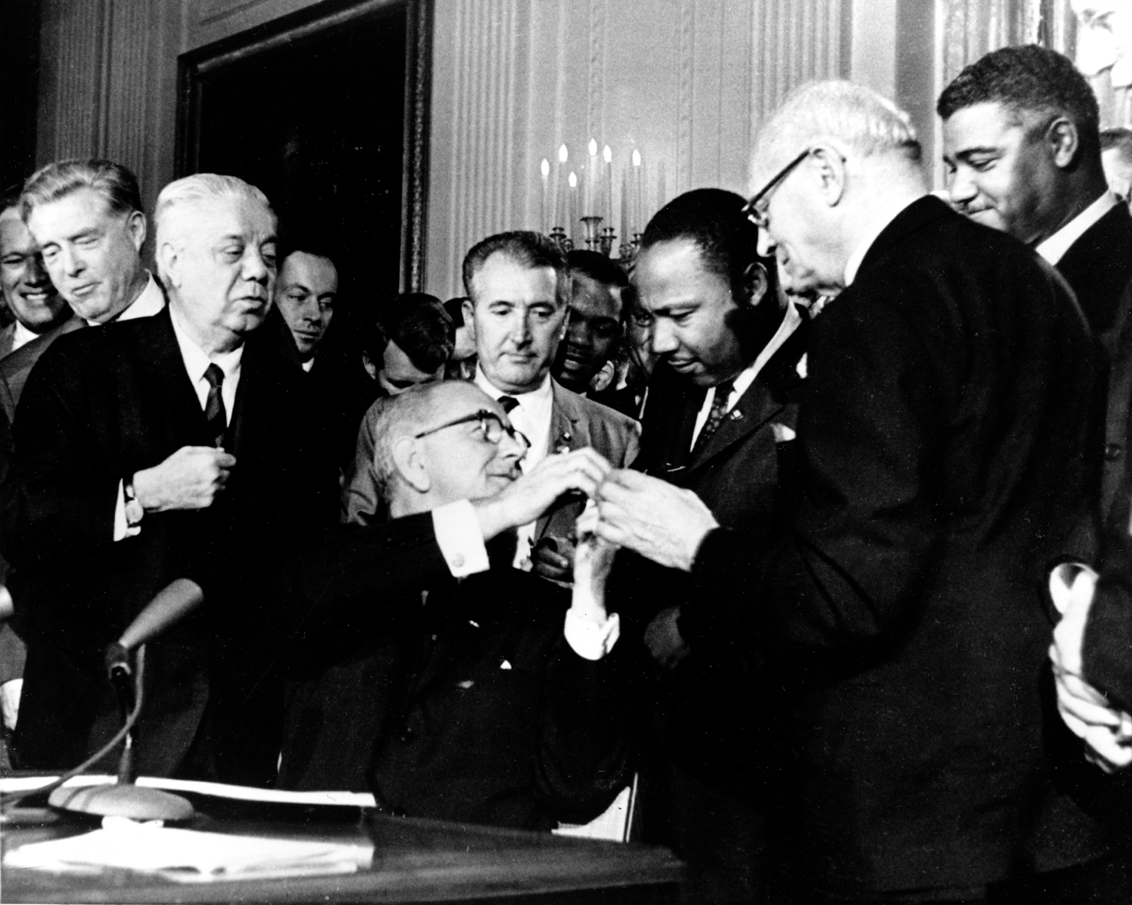 On July 2, 1964, President Lyndon B. Johnson reached to shake hands with Martin Luther King Jr. after signing the Civil Rights Act in Washington.