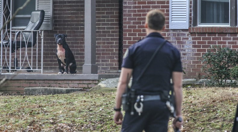 An Atlanta police office corners one of the dogs on Thurgood Street. JOHN SPINK /JSPINK@AJC.COM